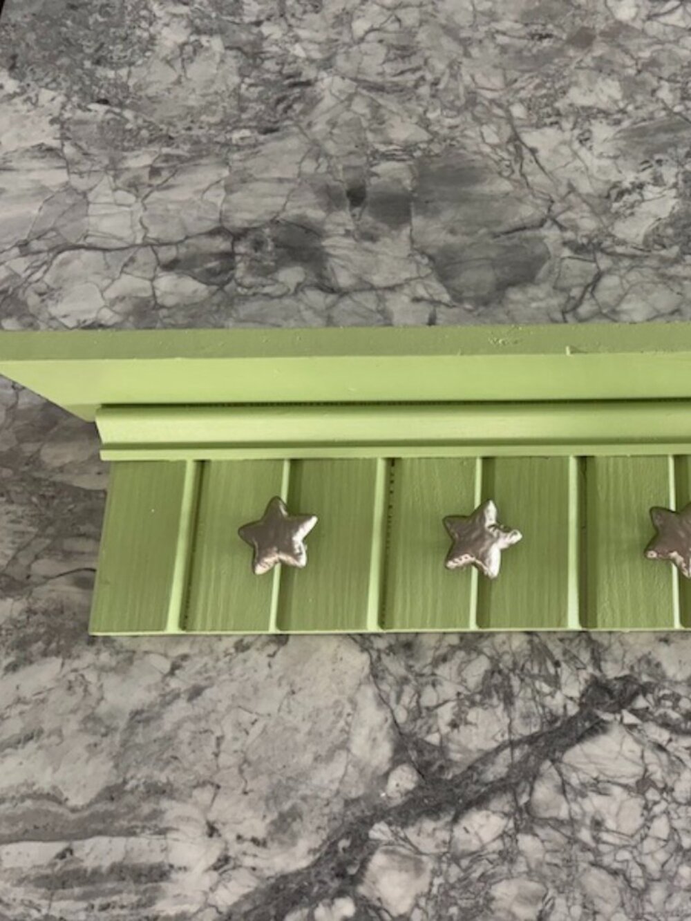 Light green, handmade wooden wall shelf with hanging star knobs for hanging